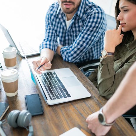 Business coworkers discussing over laptop while planning together in meeting at office